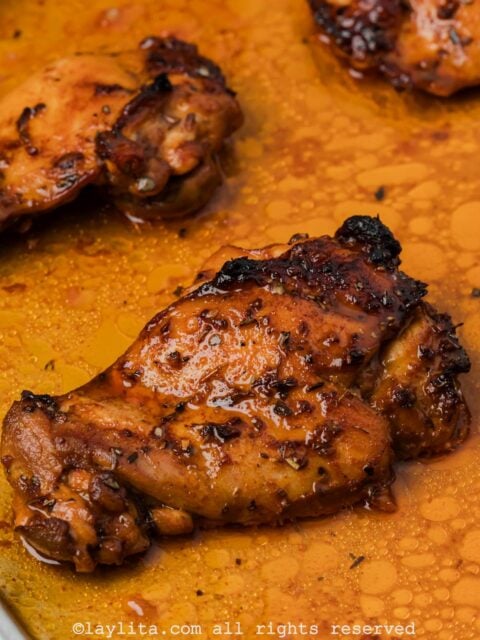 A roasted chicken thigh on a baking sheet