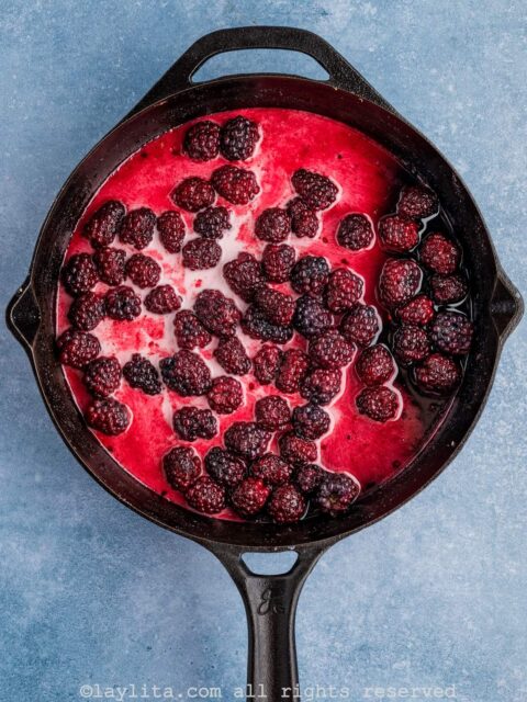 Blackberries cooking in a skillet with corn starch slurry stirred in