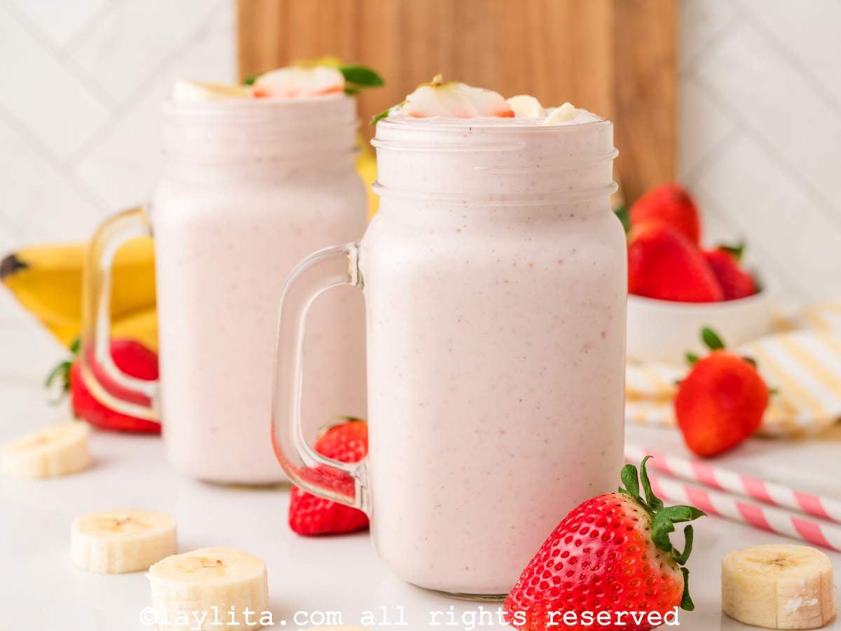 Side view of two large mason jars filled with strawberry banana milkshake