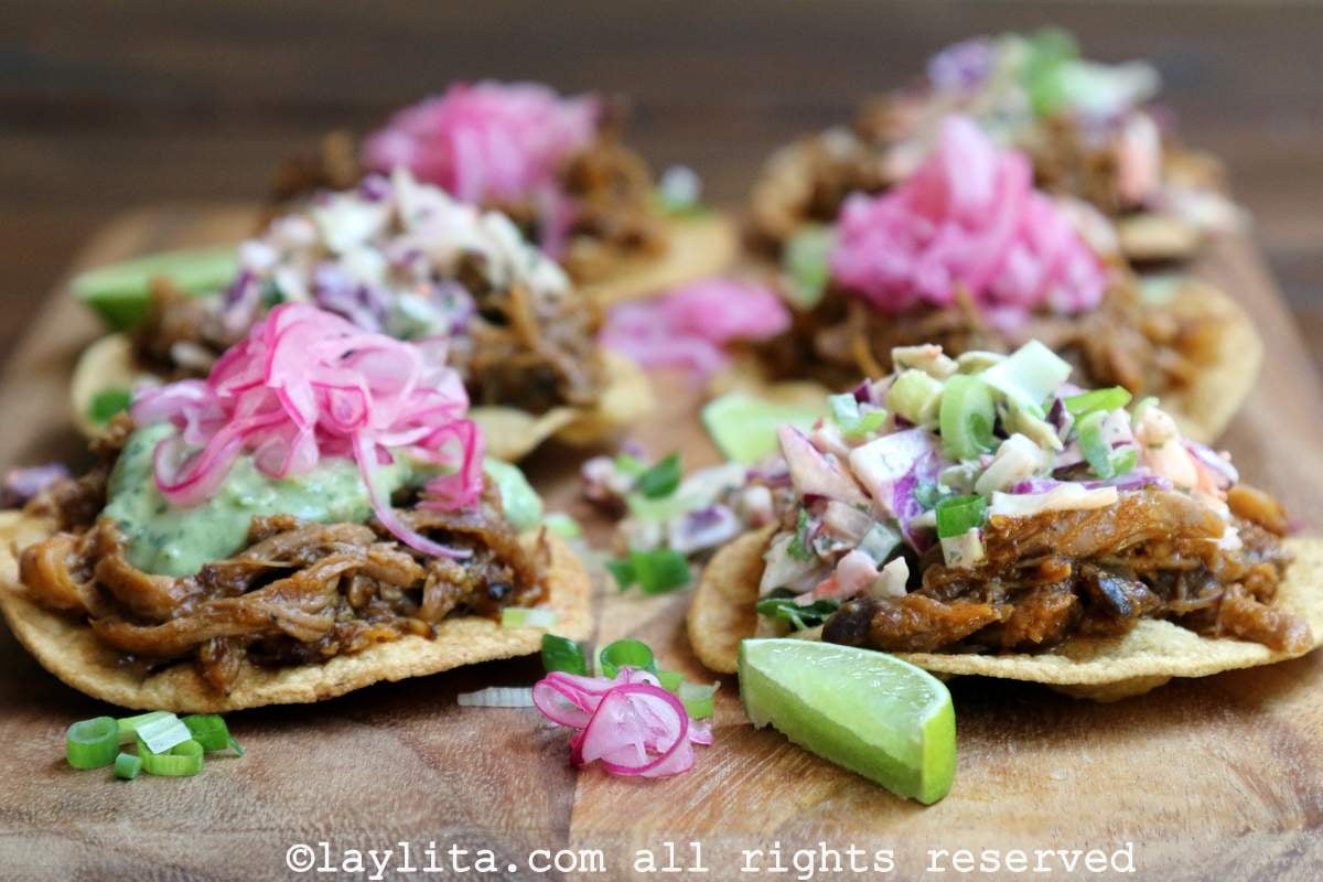 Crispy corn tostadas served with chicha pulled pork, pickled onions, avocado sauce and coleslaw on top.