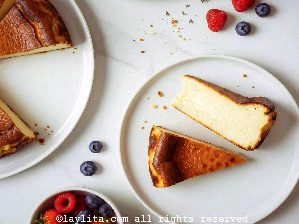 Two slices of basque cheesecake on a white plate next to fresh berries.