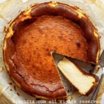 Overhead shot of a basque cheesecake on parchment paper with one slice on its side.