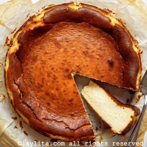 Overhead shot of a basque cheesecake on parchment paper with one slice on its side.