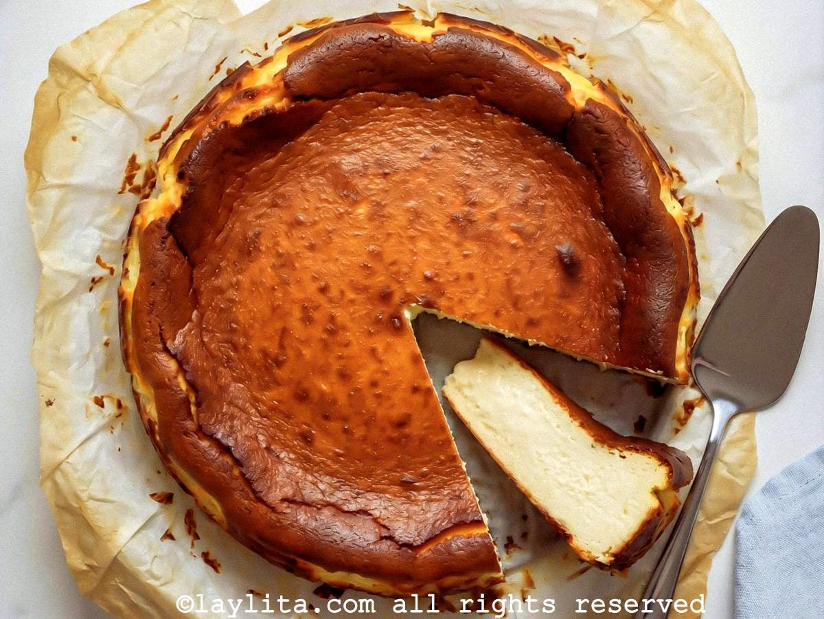 Overhead shot of a basque cheesecake on parchment paper with one slice on its side.