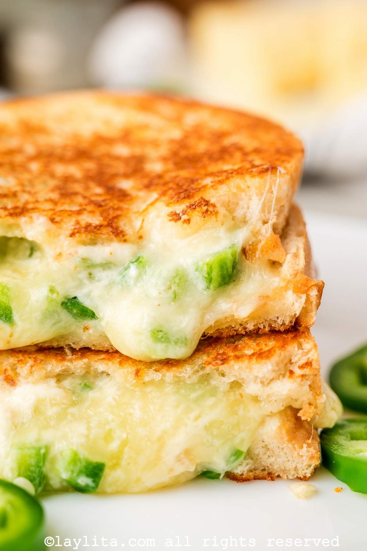 Close up of two halves of a jalapeño popper grilled cheese on top of each other on a plate. 