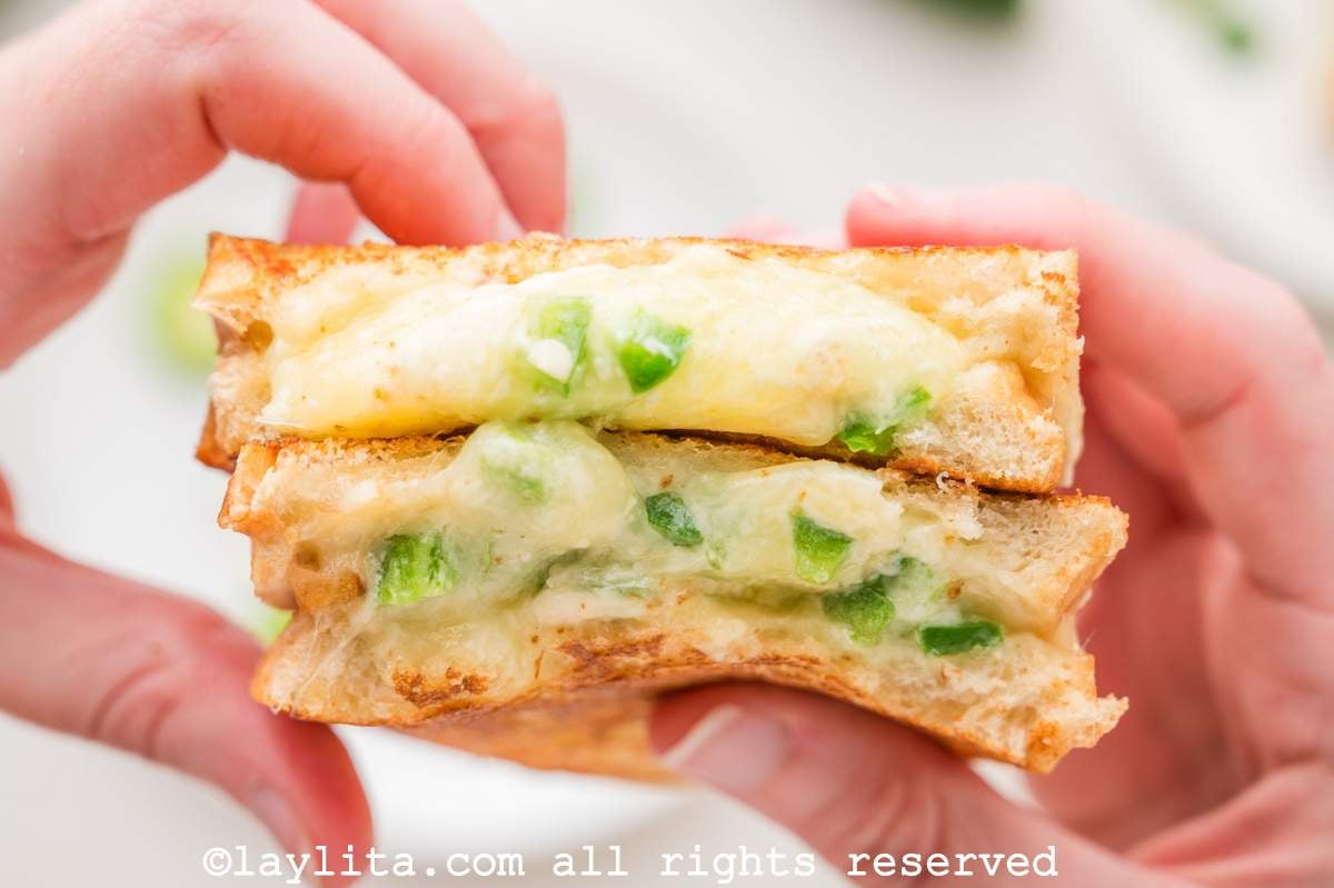 Hands holding two halves of a jalapeño popper grilled cheese