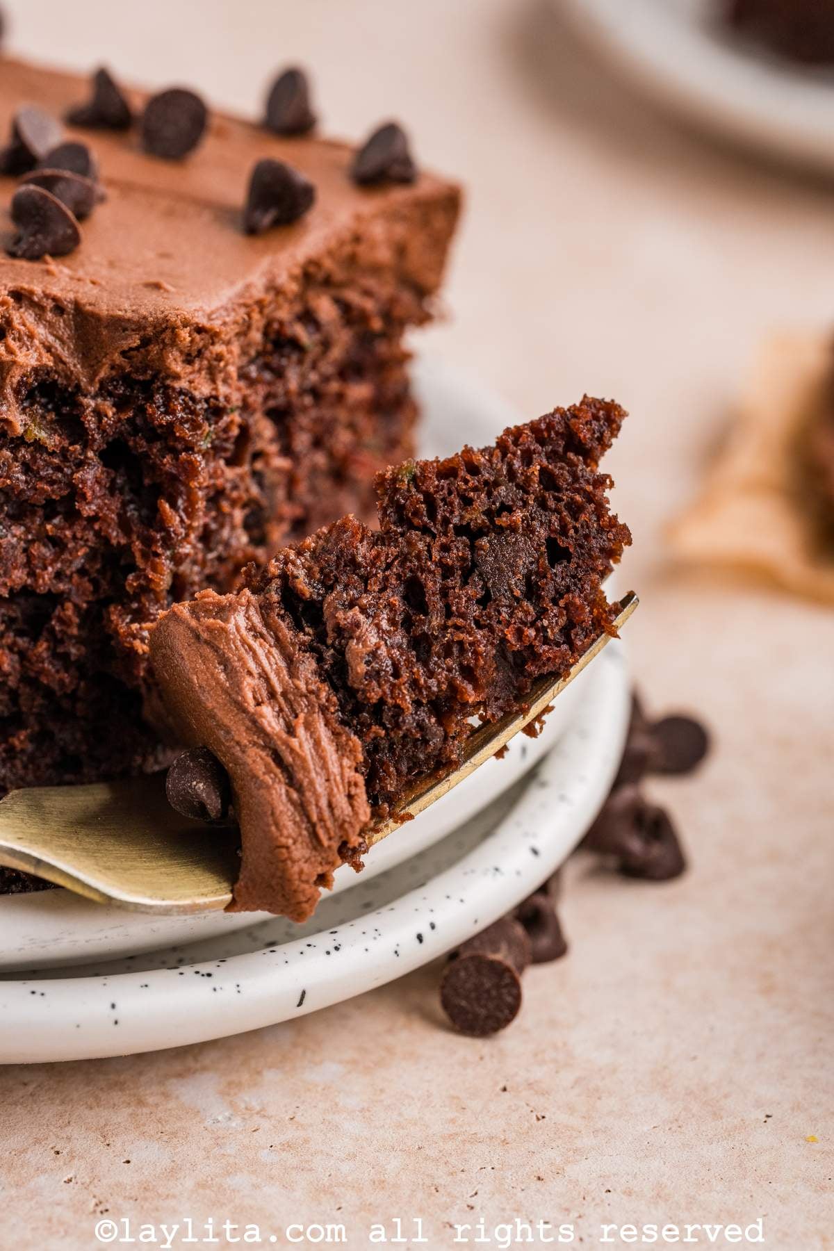 Close up of a slice of chocolate zucchini cake with a fork with a bite on it