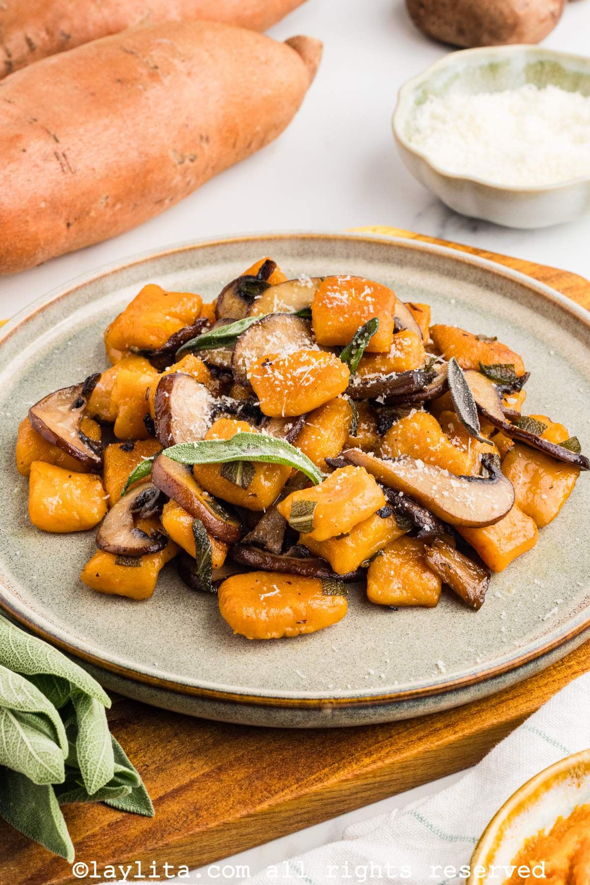 Sideview of a brown plate filled with sweet potato gnocchi sauteed with mushrooms