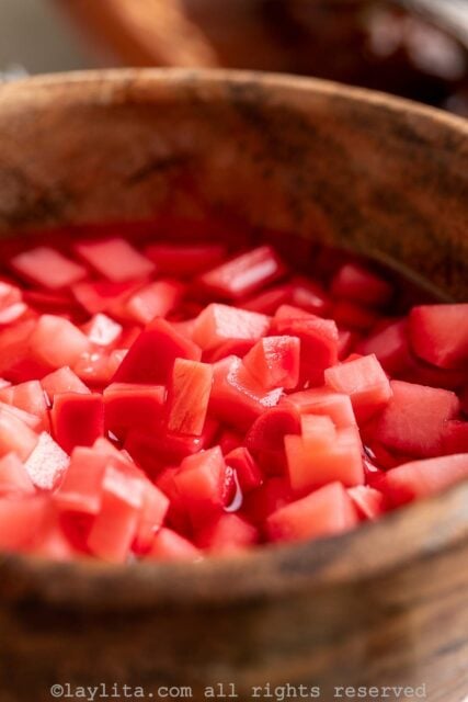 Side view of pickled diced radishes in a small wood bowl