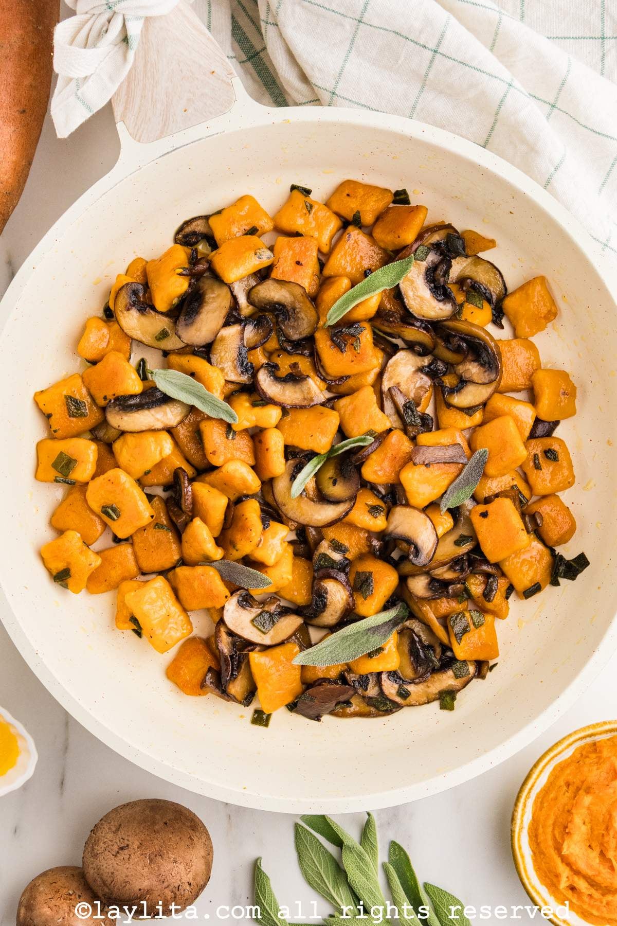 Overhead view of a skillet full of sweet potato gnocchi sauteed with mushrooms and sage