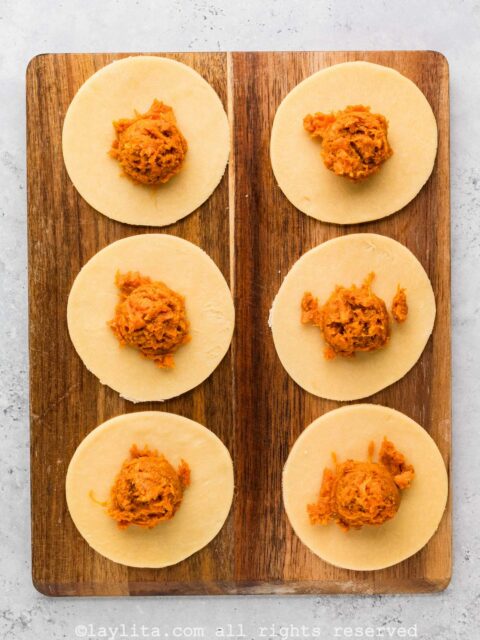 Empanada discs with sweet potato filling on a wood board