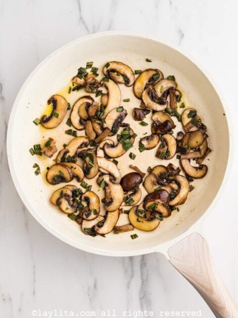 Sauteed mushroom slices with sage and butter in a white skillet