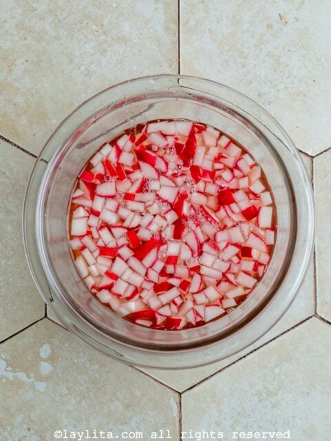 Diced radishes being pickled in a glass bowl