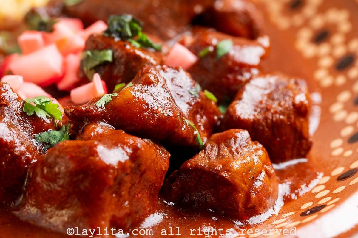 Close-up of Beef Chile Stew topped with diced pickled radishes and cilantro on a platter