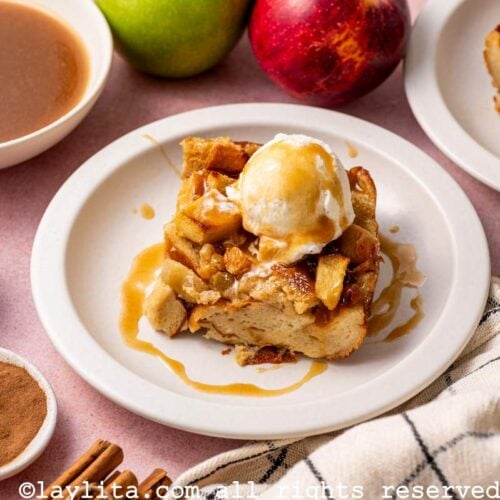 A piece of Caramel Apple Bread Pudding on a plate topped with ice cream and extra caramel sauce