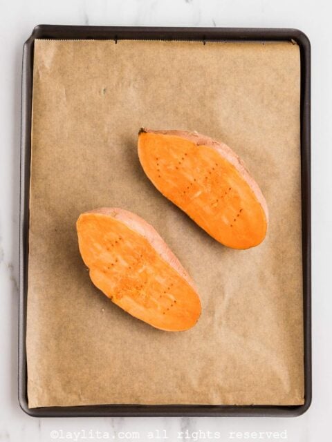 A sweet potato cut in half on a baking sheet