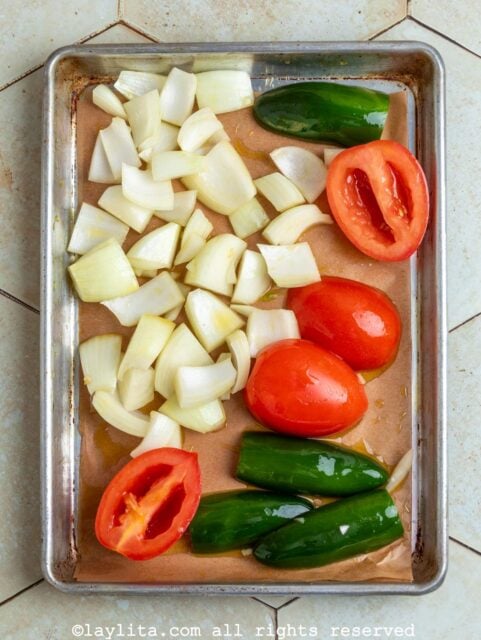 Onion chunks, tomatoes and jalapeños on a baking tray