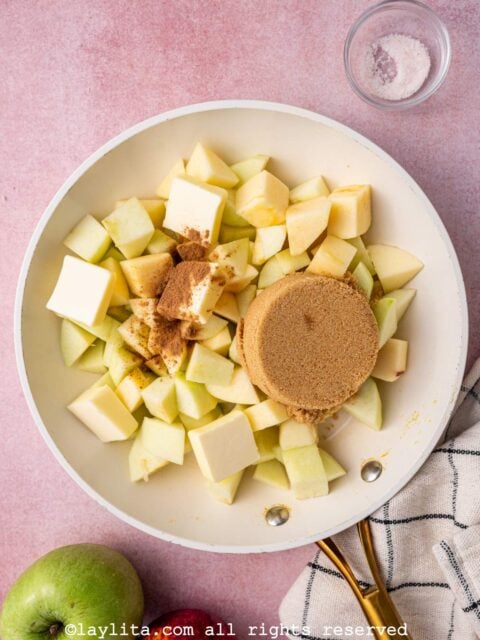 Diced apples, brown sugar, spices and butter in a white skillet