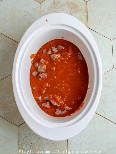 Beef pieces and red chile sauce in a slow cooker
