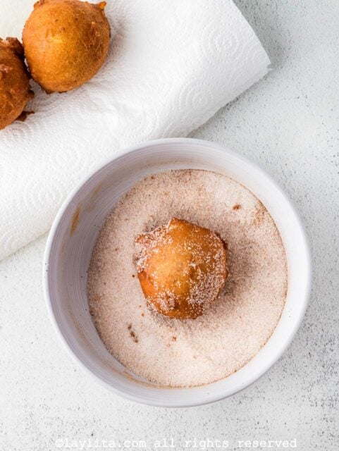Rolling the apple fritters in spiced sugar